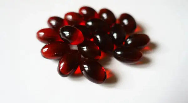 Un mucchio di capsule rosse traslucide, forse integratori di fosfatidil colina, su sfondo bianco.