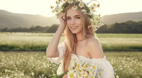 Ragazza con corona di margherite e bouquet, capelli biondi luminosi come dopo shampoo alla camomilla effetti naturali.