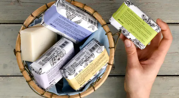 Scopri come si usa lo shampoo solido Davines: una mano sceglie una saponetta profumata da un cesto.