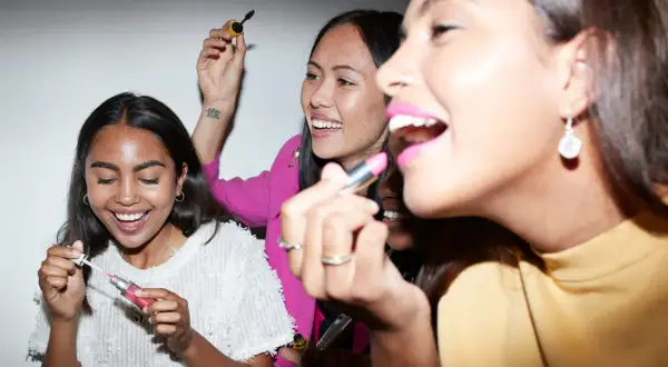 Amiche che provano diversi tipi di rossetto e mascara, ridendo e divertendosi.