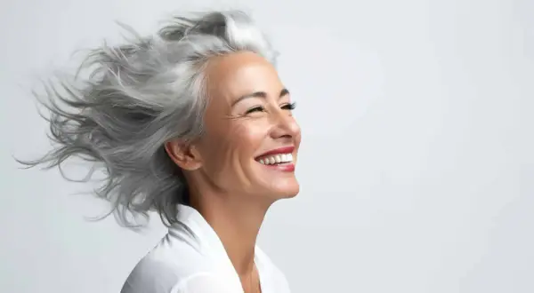 Donna sorridente con splendidi capelli bianchi mossi dal vento.