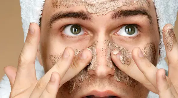 Uomo con scrub viso, pronto per la cura della pelle. Cosa mettere dopo lo scrub viso per un risultato ottimale.