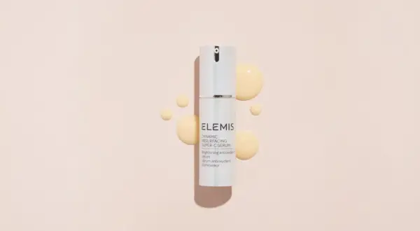 Siero ELEMIS con acido glicolico e vitamina C, per una pelle luminosa e rinnovata, circondato da gocce dorate.