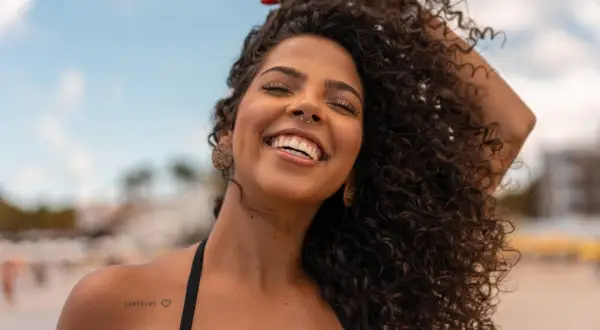 Donna sorridente con capelli ricci e fluenti, un esempio di come trattare i capelli ricci per un look naturale e radioso.