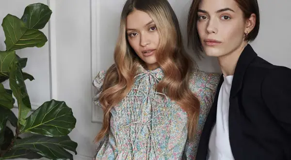 Due modelle con capelli biondi e castani, una con abito floreale, l'altra con blazer. L'armocromia inverno capelli valorizza i loro toni.