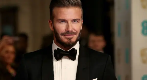 Uomo con impeccabili capelli all'indietro, barba curata e smoking nero con papillon.