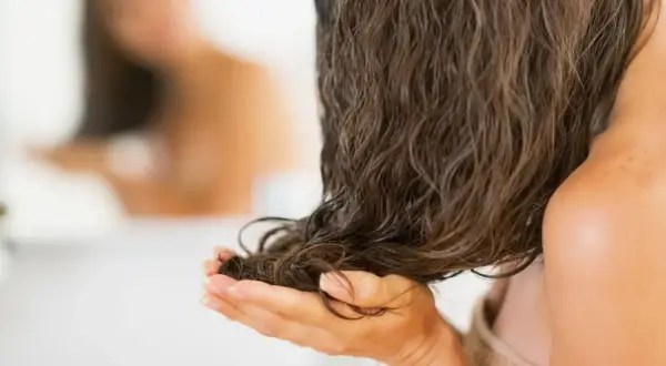 Mani che accarezzano capelli lunghi e bagnati, pronti per dormire con i capelli bagnati e svegliarsi con onde naturali.