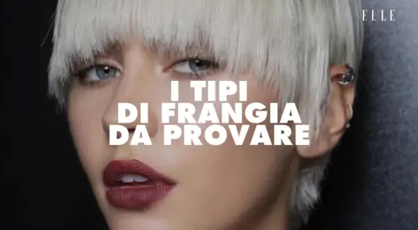 Modella con capelli biondo platino e una frangia corta che incornicia il viso. Labbra rosse e occhi azzurri intensi. Testo: "I tipi di frangia da provare".