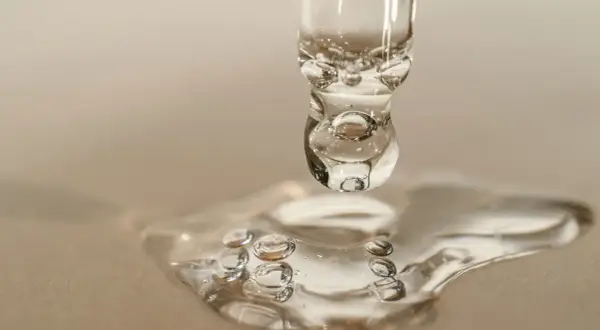 Goccia di siero con retinolo, che riflette la luce come il sole. La sua consistenza trasparente e le bollicine catturano l'essenza della cura della pelle.