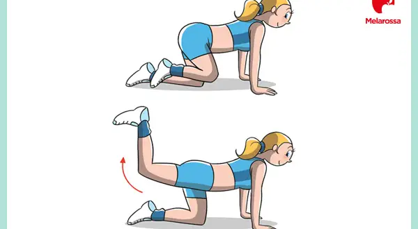 Donna in posizione quadrupedica esegue un esercizio per ottenere glutei perfetti. Solleva una gamba all'indietro.