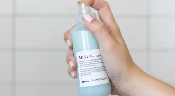 Mano che spruzza siero per capelli MINU. Scopri come si usa il siero per capelli per un colore luminoso e intenso.