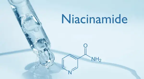 Goccia di siero trasparente da un contagocce, con la formula chimica e il nome "Niacinamide" che indica cos'è la niacinamide.