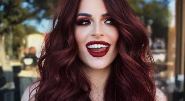 Capelli color cherry cola, labbra rosse audaci e uno sguardo malizioso.
