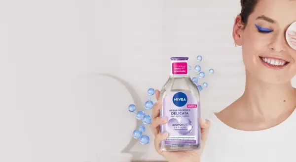 Donna sorridente rimuove il trucco con acqua micellare Nivea, mostrando come si usa acqua micellare per una pulizia delicata.