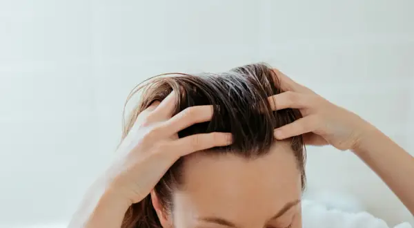 Mani che massaggiano il cuoio capelluto per alleviare la forfora secca.