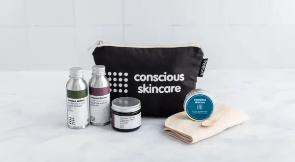 Kit skincare viso con borsa nera, flaconi, crema e maschera.