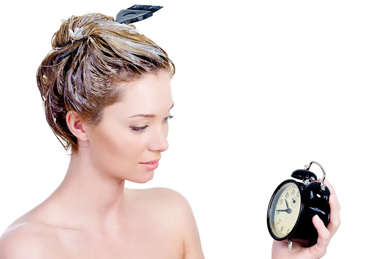 Donna con capelli trattati con maschera, osserva un orologio. Impara come si usa la maschera per capelli per un trattamento efficace.
