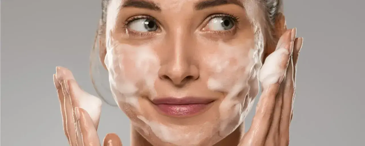 Donna con schiuma sul viso, che mostra come si usa il detergente viso per una pulizia profonda e delicata.