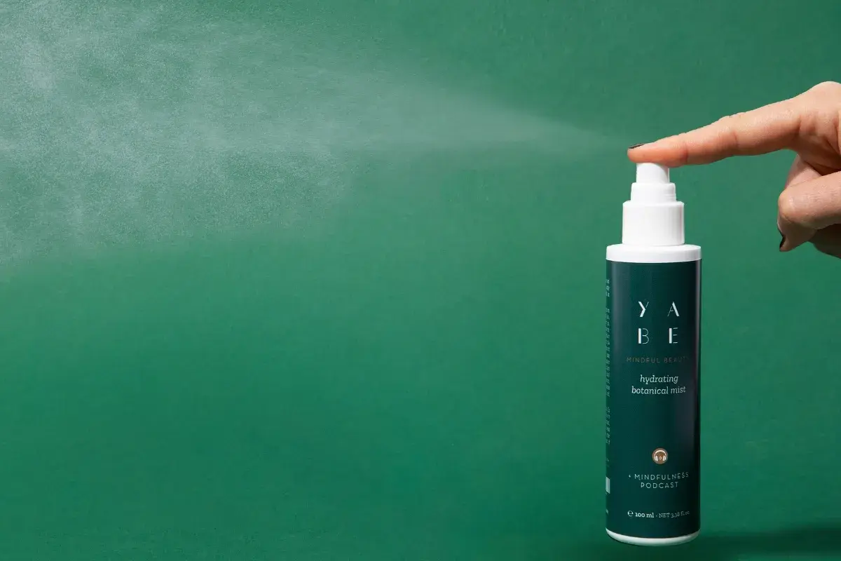 Un dito preme il vaporizzatore di un tonico viso idratante, un gesto che rinfresca e rivitalizza la pelle.
