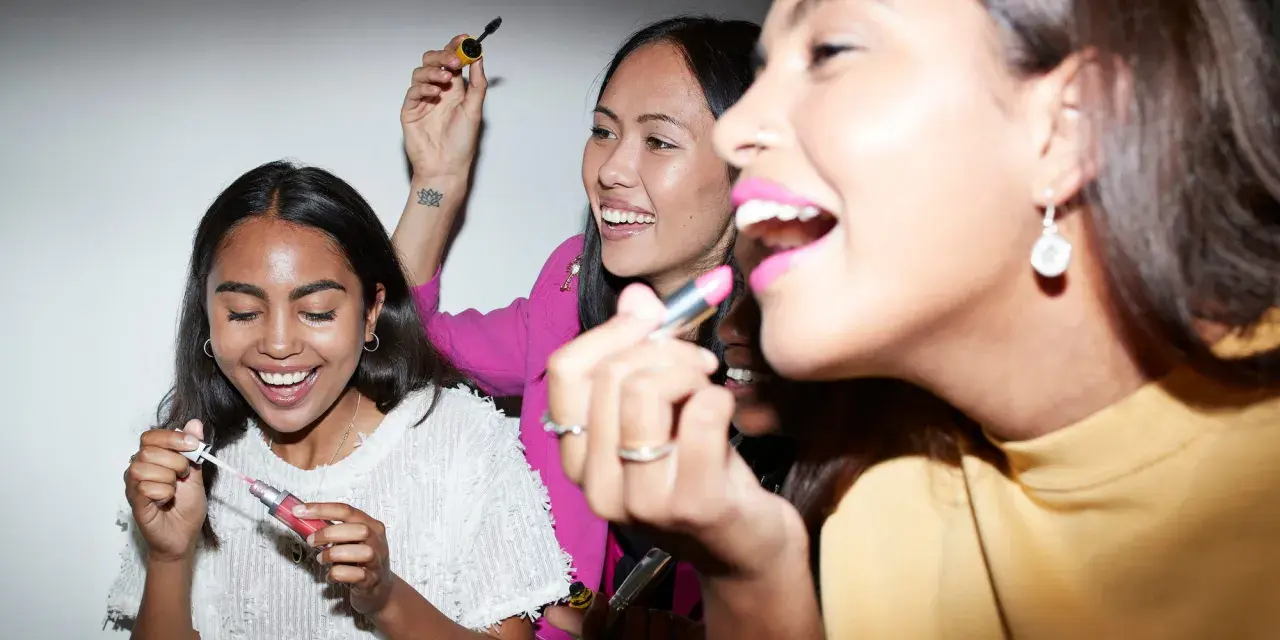 Amiche che provano diversi tipi di rossetto e mascara, ridendo e divertendosi.