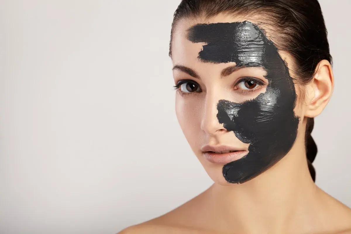 Donna con maschera al carbone sul viso, per scoprire i benefici di una pelle purificata e luminosa.