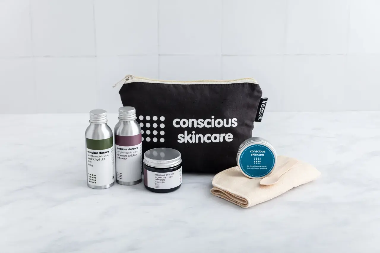 Kit skincare viso con borsa nera, flaconi, crema e maschera.