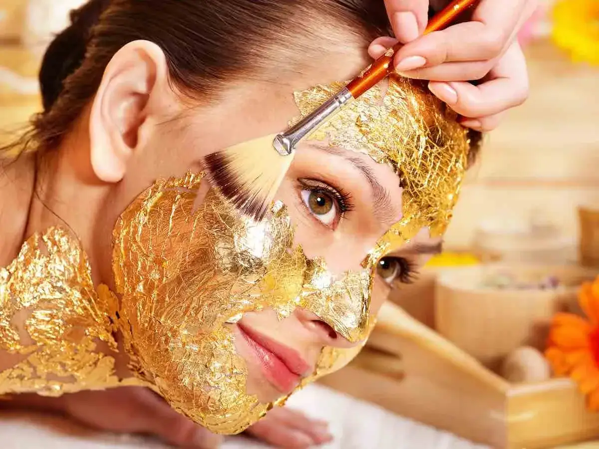 Una donna riceve un trattamento di bellezza con una maschera viso oro, scoprendo i suoi benefici rigeneranti e illuminanti.