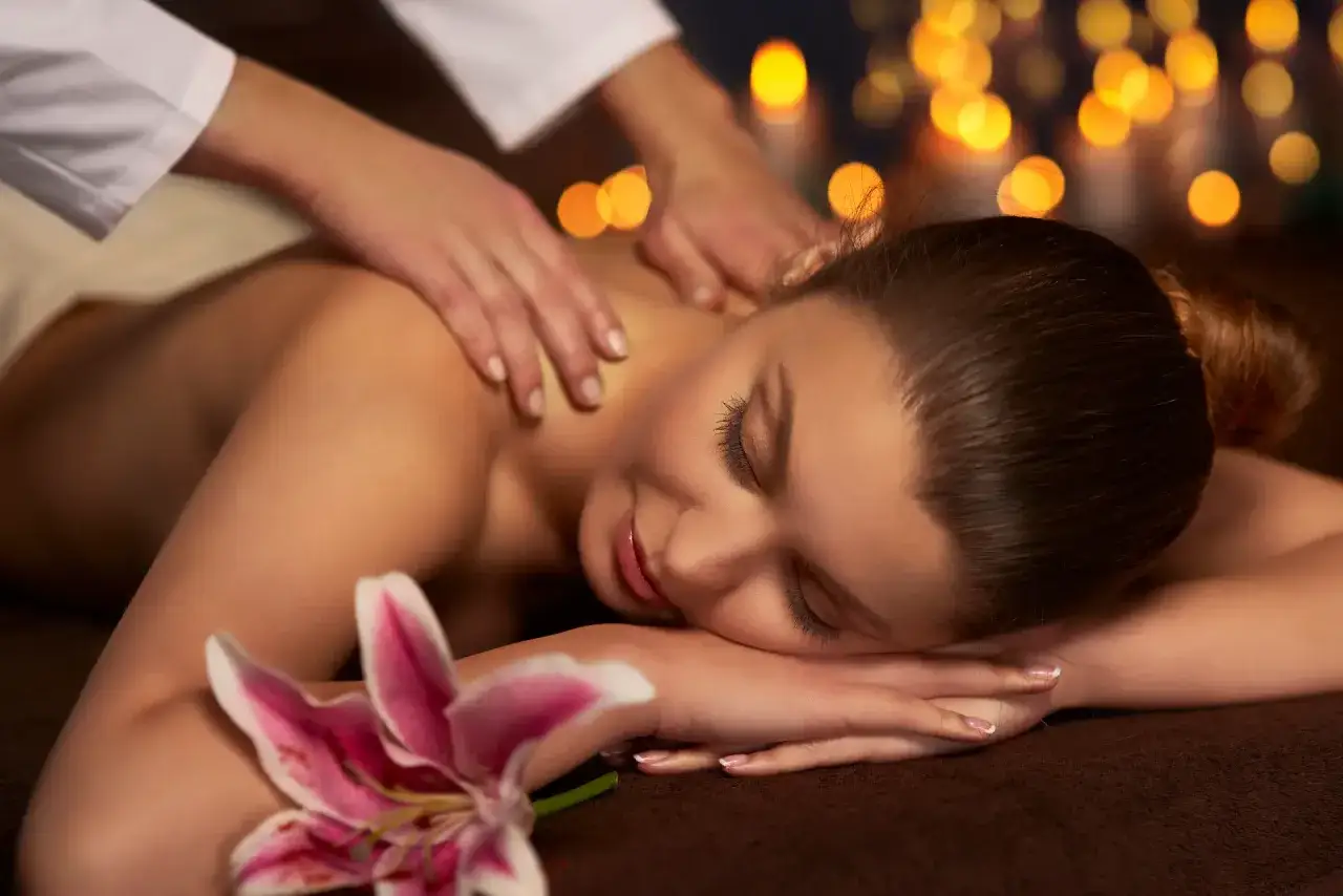 Rilassante massaggio olistico corpo a corpo con luci soffuse e un fiore di giglio.