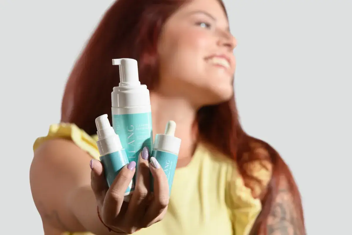 Donna sorridente mostra prodotti per il viso, ideali per chi cerca come eliminare il sebo in eccesso dal viso.