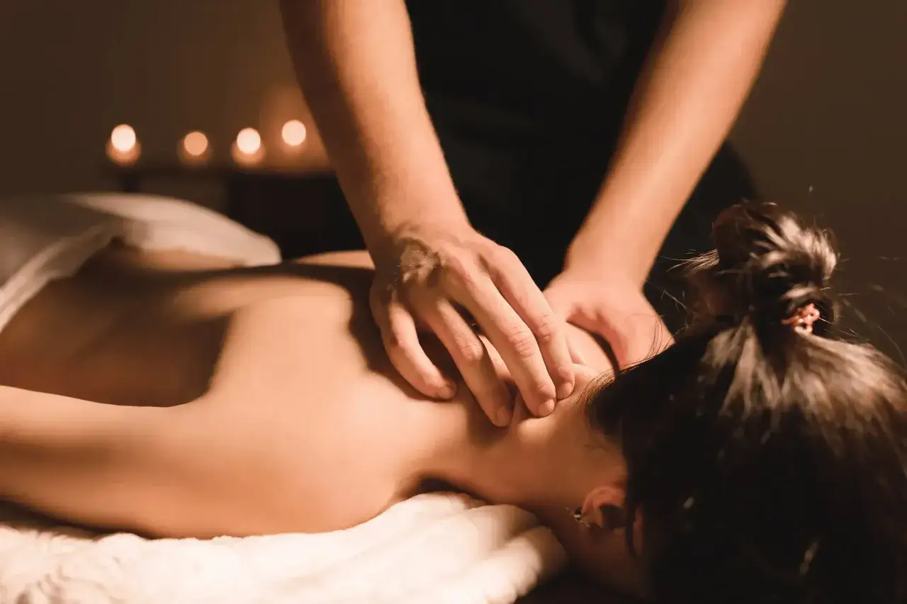 Mani esperte eseguono un massaggio svedese total body, sciogliendo tensioni su collo e spalle. Luci soffuse e candele creano un'atmosfera rilassante.