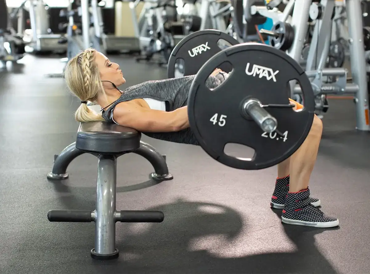 Donna esegue un hip thrust con bilanciere, un esercizio chiave per come avere un bel sedere tonico e forte.