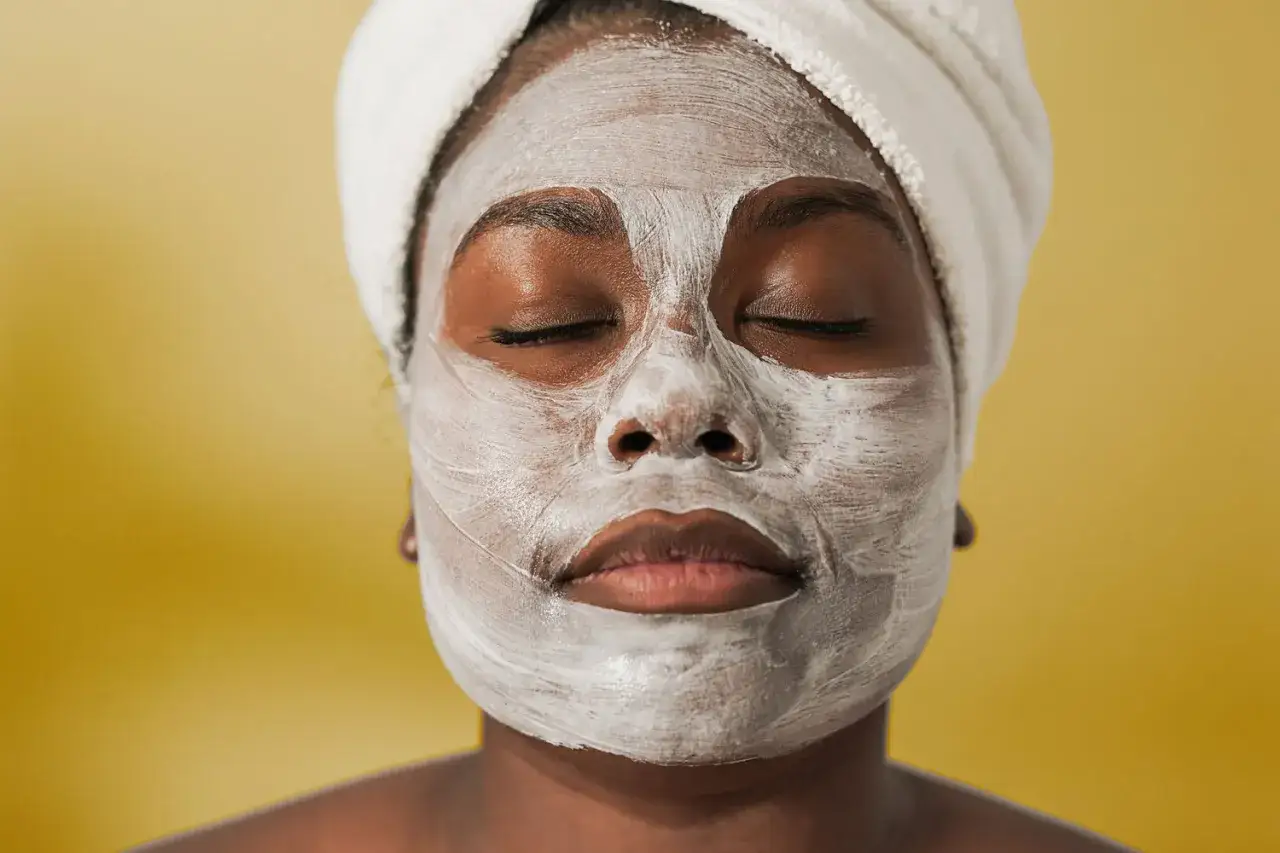Donna con maschera viso bianca e turbante, occhi chiusi, pronta per quando dopo la maschera si sciacqua il viso.