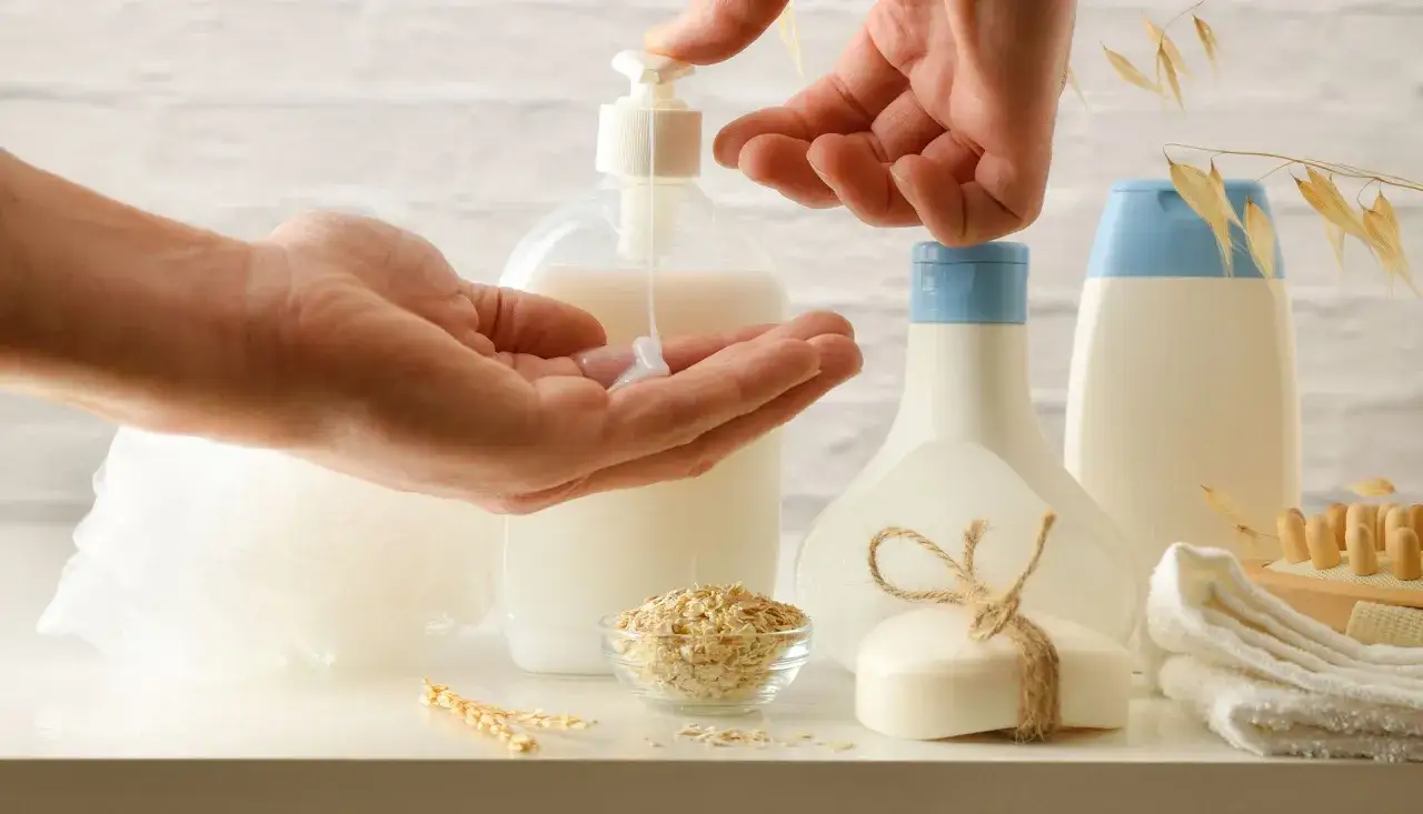 Mani che versano lozione, avena e sapone. Scopri gli avena benefici capelli per una chioma sana e luminosa.