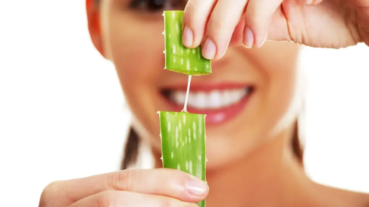 Goccia di gel di aloe vera che cade da un pezzo di foglia a un altro, mostrando i benefici per la pelle.