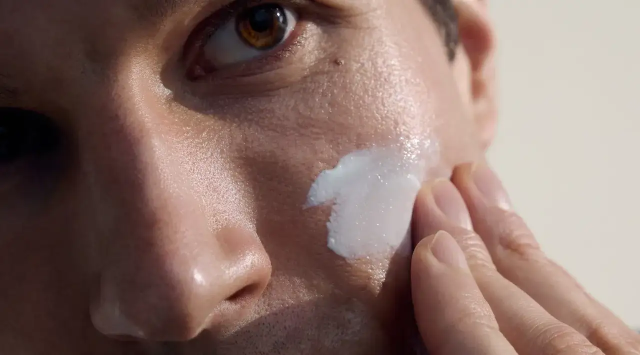 Un uomo applica una crema idratante sul viso. Un gesto semplice per un kit pulizia viso uomo efficace.