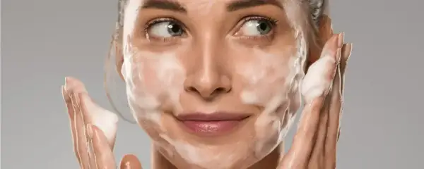 Donna con schiuma sul viso, che mostra come si usa il detergente viso per una pulizia profonda e delicata.