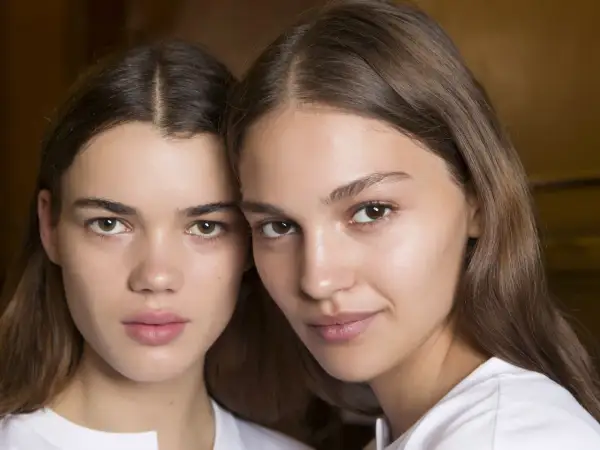 Close-up of two young women with brown hair and natural makeup.