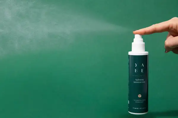 Un dito preme il vaporizzatore di un tonico viso idratante, un gesto che rinfresca e rivitalizza la pelle.