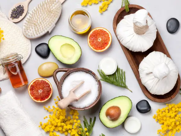 Ingredienti per uno scrub fatto in casa: sale, avocado, arancia, miele, lavanda e una spazzola per il corpo.