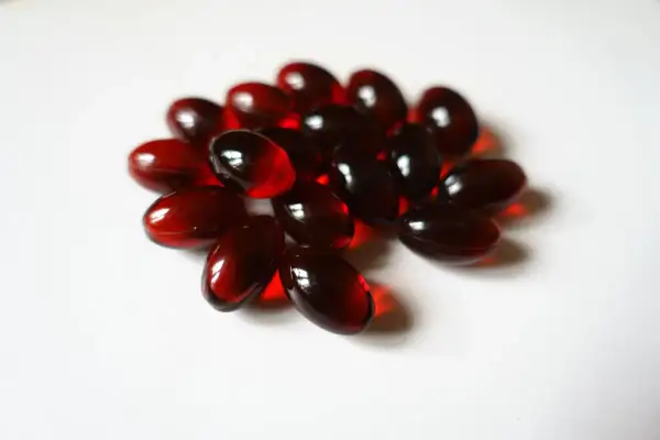 Un mucchio di capsule rosse traslucide, forse integratori di fosfatidil colina, su sfondo bianco.