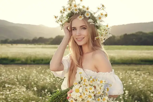 Ragazza con corona di margherite e bouquet, capelli biondi luminosi come dopo shampoo alla camomilla effetti naturali.