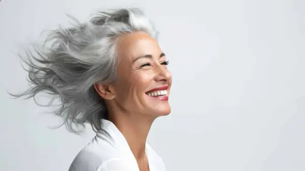 Donna sorridente con splendidi capelli bianchi mossi dal vento.