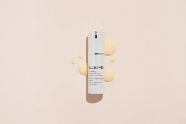 Siero ELEMIS con acido glicolico e vitamina C, per una pelle luminosa e rinnovata, circondato da gocce dorate.