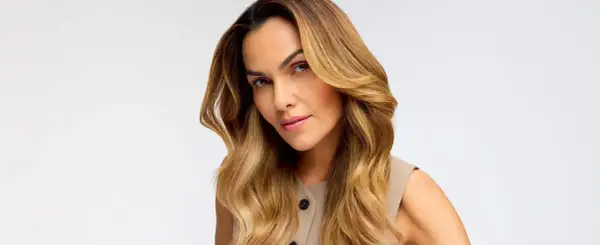 Donna con capelli biondo miele, effetto colpi di sole fai da te, che incorniciano il viso con onde morbide.