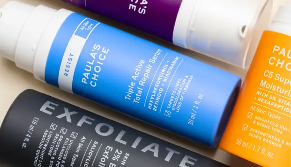 Flaconi di prodotti per la cura della pelle, tra cui un siero con retinolo e vitamina c, per una routine anti-età completa.