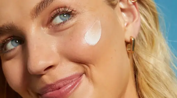 Primo piano di una donna con crema sul viso. L'acido salicilico per la pelle aiuta a ottenere un incarnato luminoso e uniforme.
