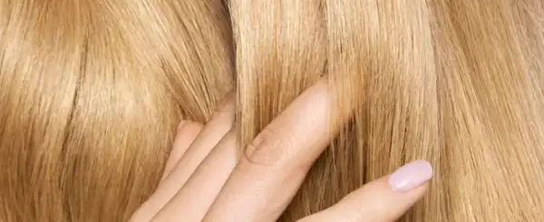 Dita accarezzano capelli biondi e setosi. Posso usare la maschera per capelli prima dello shampoo per ottenere questa morbidezza.