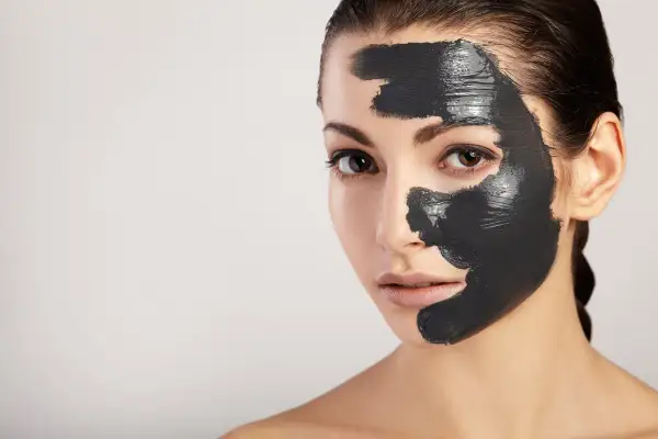 Donna con maschera al carbone sul viso, per scoprire i benefici di una pelle purificata e luminosa.