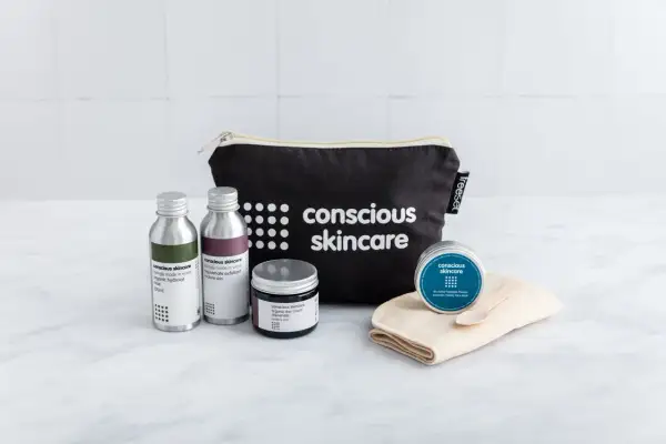 Kit skincare viso con borsa nera, flaconi, crema e maschera.